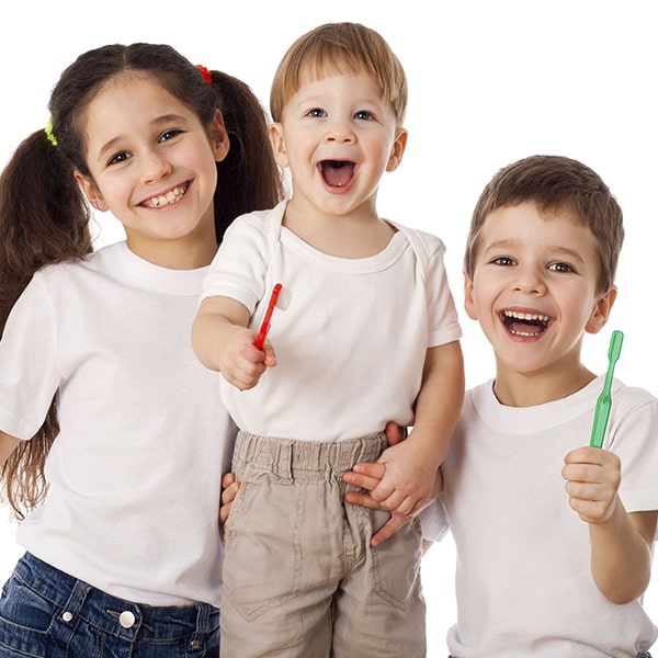 Three children smiling and holding tooth brushes.